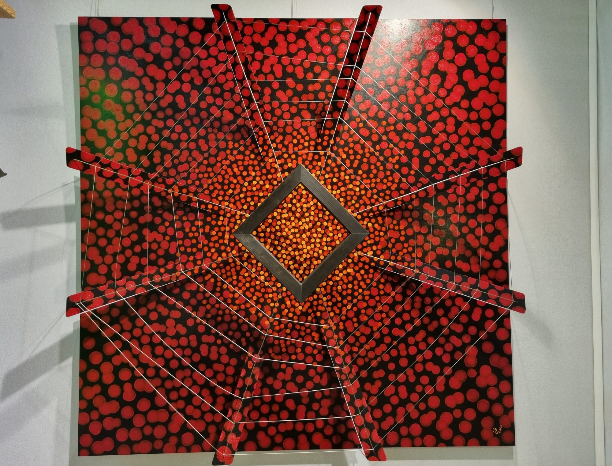 Œuvre abstraite avec motifs rouges et noirs, forme carrée au centre.