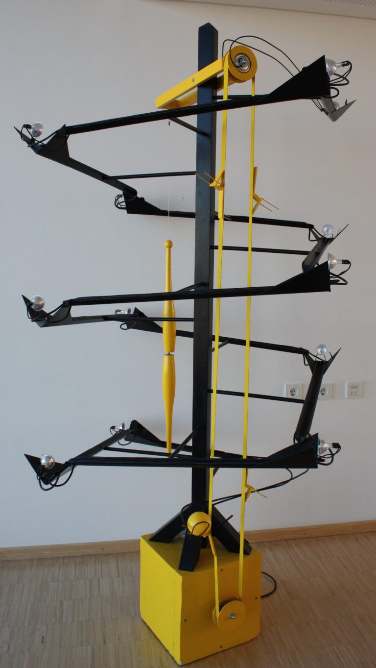 Système de suspension en métal noir et jaune, avec plusieurs bras en cascade.