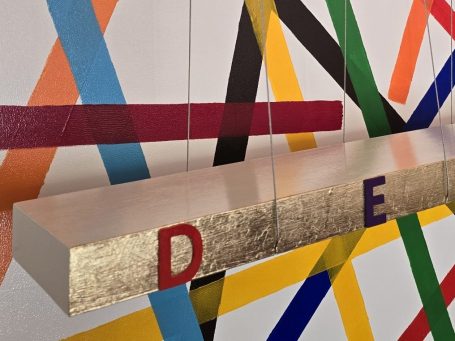 Democracy Lettres colorées suspendues devant un fond de bandes colorées.