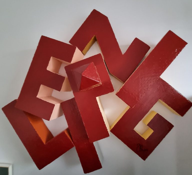 Composition de lettres en rouge et jaune, formant une sculpture abstraite.