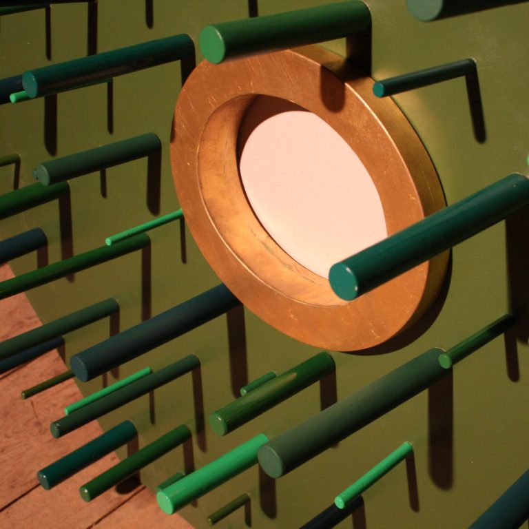 Mur vert avec des tiges en relief et un cercle doré au centre.